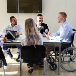 workplace meeting around table, includes man in wheelchair